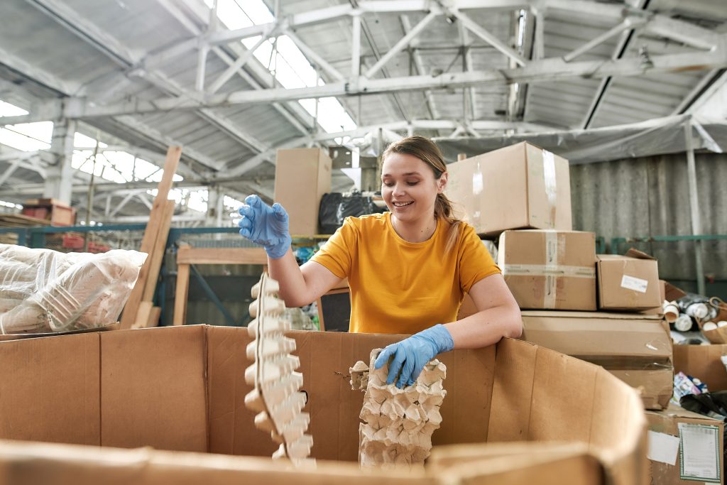 Smiling worker packaging egg trays in a warehouse
