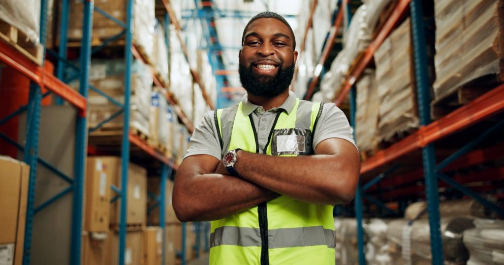 Smiling worker in warehouse with high visibility vest