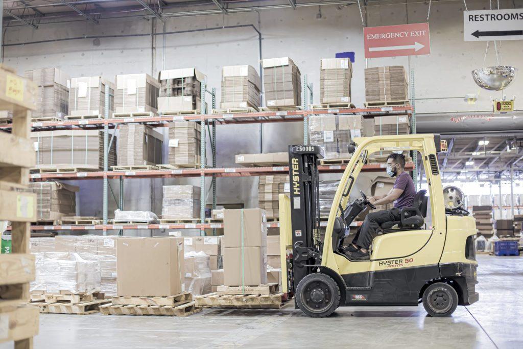 Forklift driver in NewStream warehouse transporting pallets and boxes